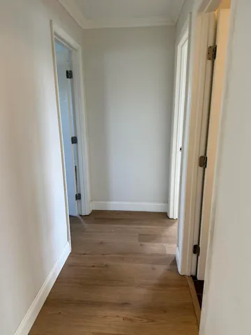 a view of a hallway with wooden floor and a door