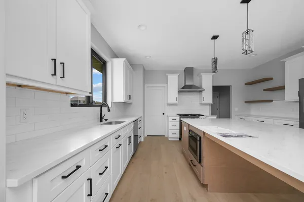 a kitchen with stainless steel appliances granite countertop a sink a stove a refrigerator and island with wooden floor