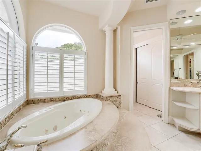 a bathroom with a tub a sink and a large window