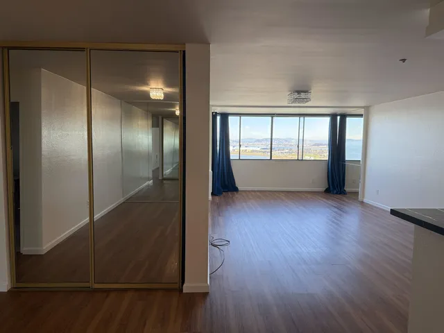 an empty room with wooden floor and windows