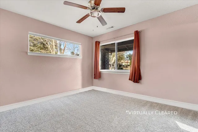 an empty room with windows and fan