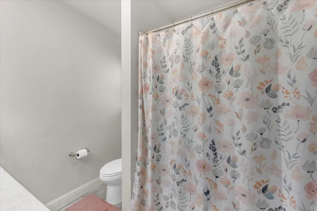 a bathroom with a granite countertop white toilet and a shower curtain