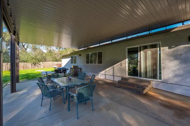 a view of a patio with table and chairs next to a yard