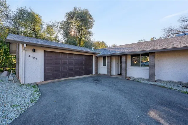 a view of a yard in front of a house with large trees