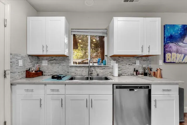 a kitchen with stainless steel appliances granite countertop white cabinets sink and window
