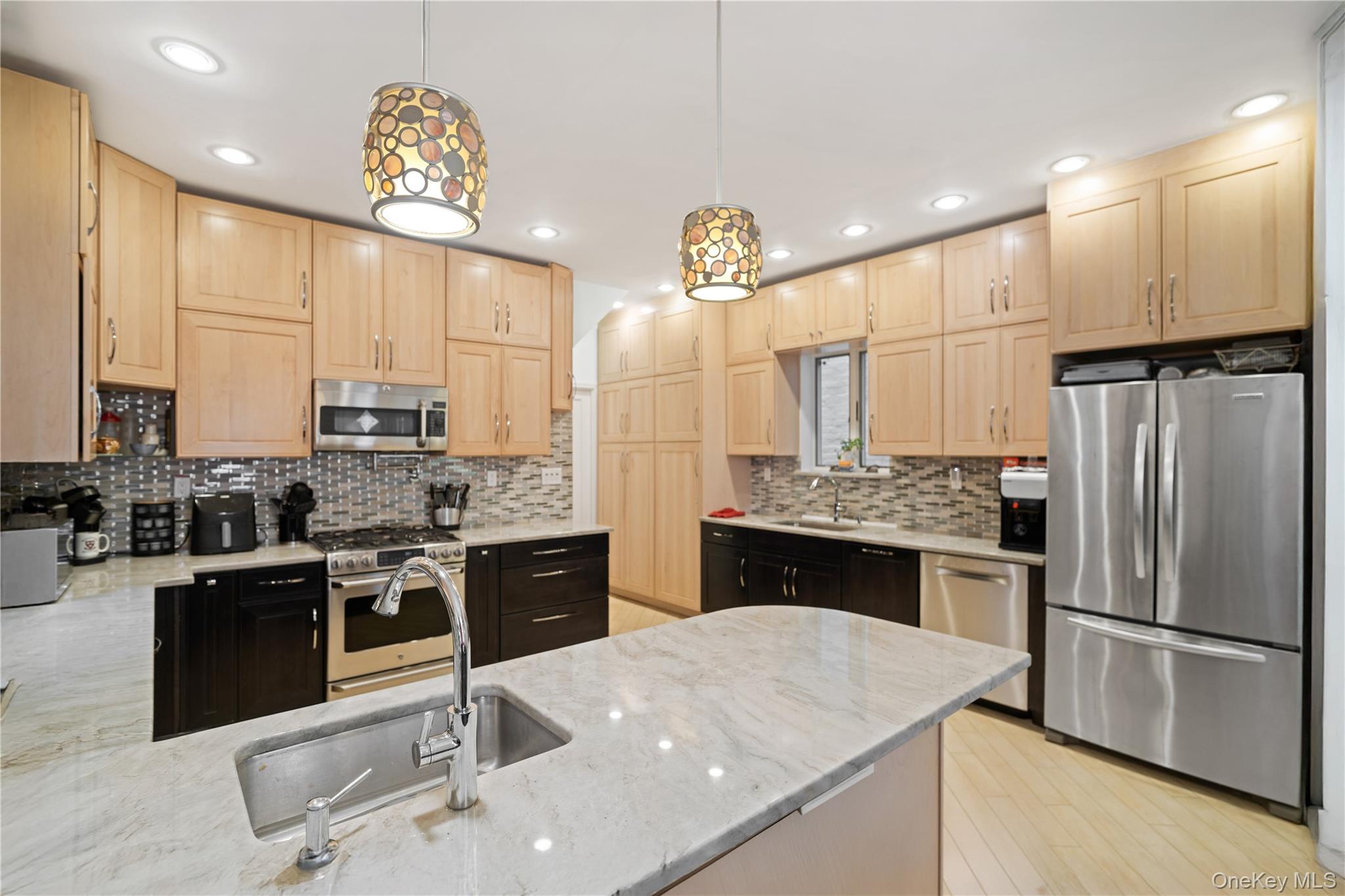 1527 East 29th Street Brooklyn, NY 11229 - Photo 5 of 22 Kitchen featuring light brown cabinetry, a peninsula, stainless steel appliances, light stone countertops, and tasteful backsplash
