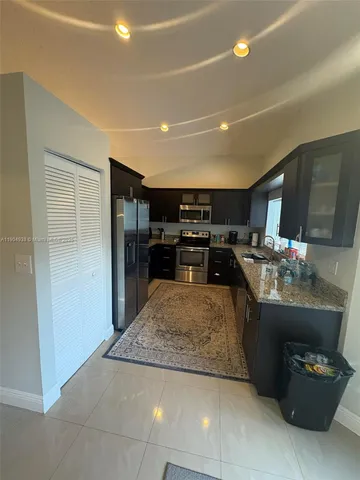a living room with stainless steel appliances kitchen island granite countertop furniture and a refrigerator
