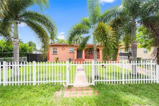a view of a house with a small yard and a large tree