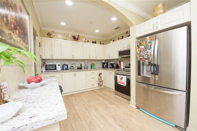 a kitchen with kitchen island a refrigerator and a stove top oven