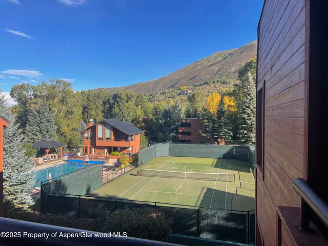 a view of a tennis ground with large trees