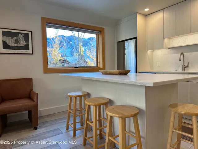 a kitchen with stainless steel appliances a dining table chairs and a refrigerator