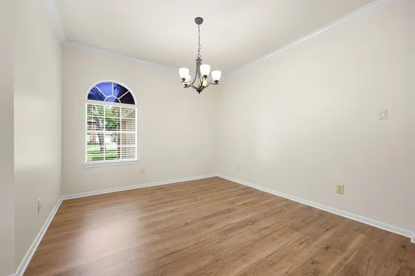 an empty room with wooden floor ceiling fan and windows