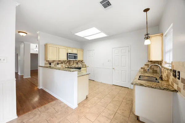 a kitchen with granite countertop cabinets stainless steel appliances a sink and a window