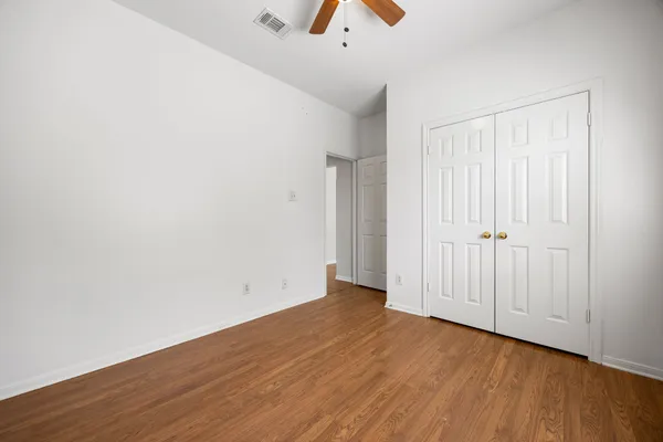 an empty room with wooden floor and a ceiling fan