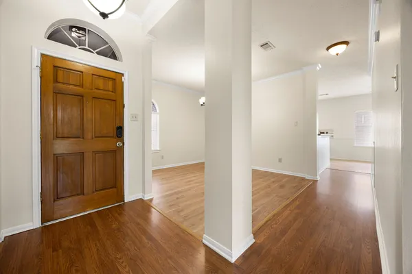 a view of an empty room with wooden floor fireplace and a window