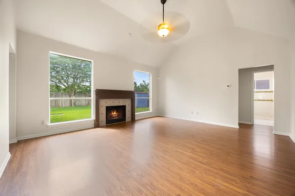 a view of an empty room with wooden floor and a window