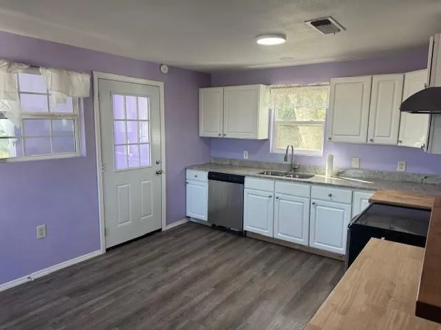 a kitchen with granite countertop a sink cabinets wooden floor and stainless steel appliances