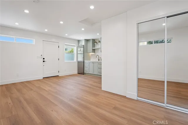an empty room with wooden floor and entrance to other room