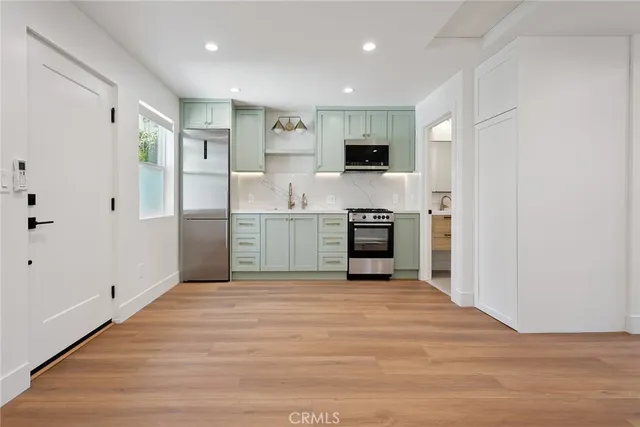 a view of kitchen with stainless steel appliances kitchen island wooden floor and window