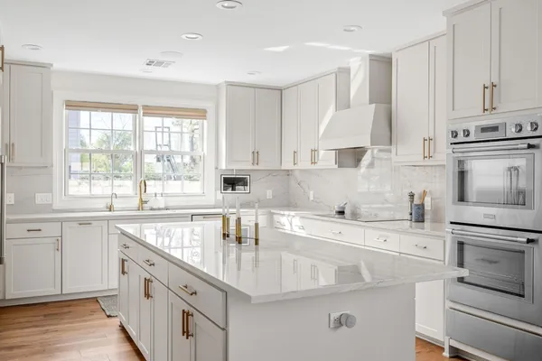 a kitchen with white cabinets appliances a sink and a window