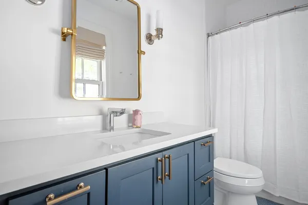 a bathroom with a granite countertop sink a toilet and a mirror