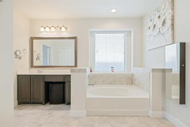 a bathroom with a tub a sink and a large mirror