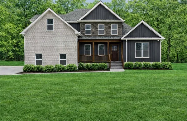 a front view of a house with a yard and green space