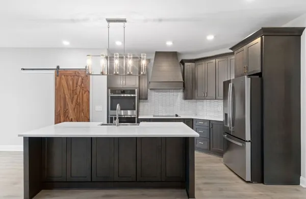 a kitchen with kitchen island granite countertop a refrigerator and a sink