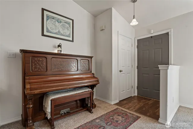 a view of hallway with a piano and wooden floor