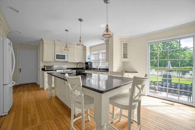 a kitchen with stainless steel appliances granite countertop a stove a refrigerator a sink dishwasher a dining table and chairs with wooden floor