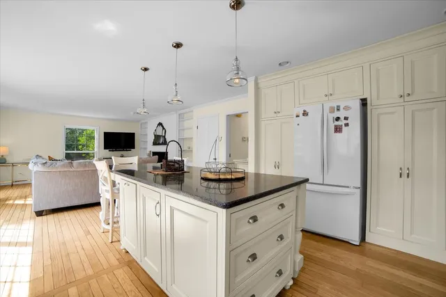 a kitchen with stainless steel appliances granite countertop a refrigerator a sink dishwasher a oven and a dining table with wooden floor