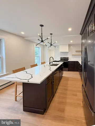 a large kitchen with stainless steel appliances kitchen island granite countertop a large counter top and wooden floors
