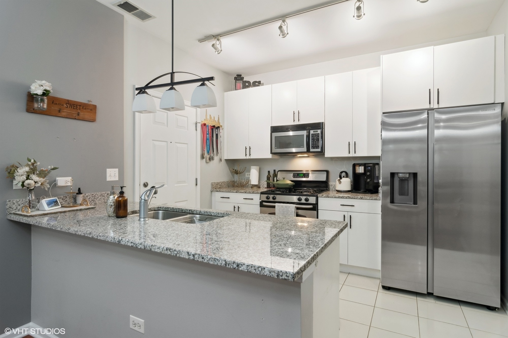 1451 South Halsted Street, Unit 2A Chicago, IL 60607 - Photo 5 of 10 a kitchen with granite countertop a sink a center island stainless steel appliances and cabinets