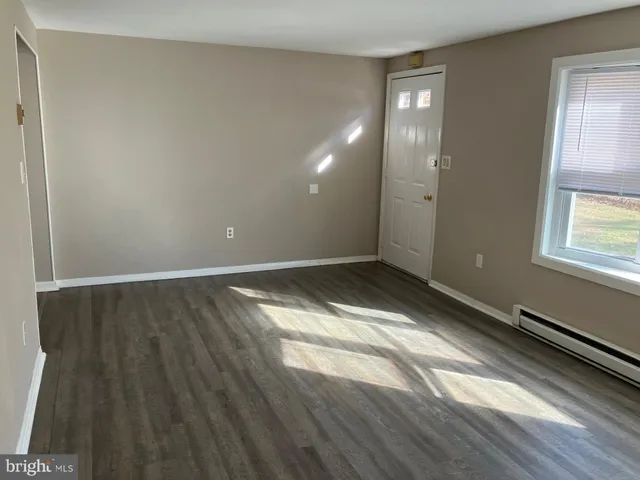 a view of empty room with window and wooden floor