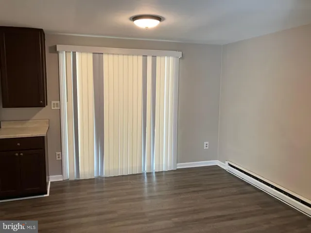 a view of an empty room with wooden floor and a fireplace