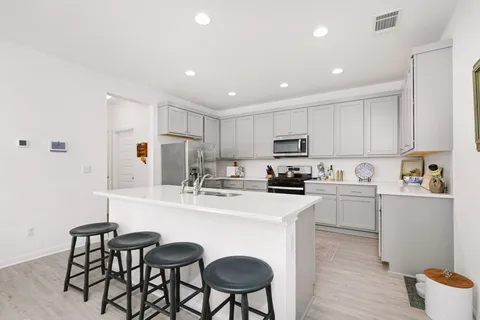 a kitchen with refrigerator a sink and chairs