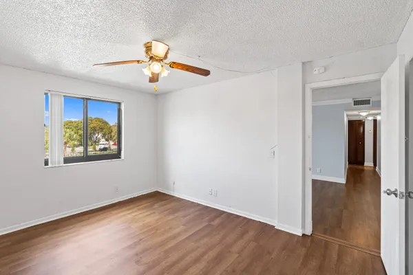 an empty room with wooden floor and a ceiling fan