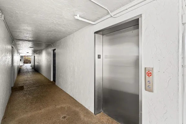 a view of a kitchen and an empty room with wooden floor