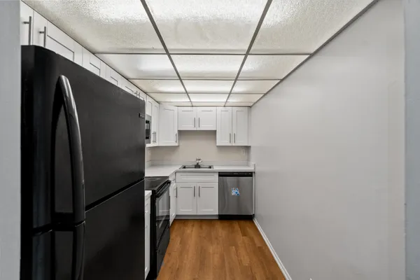 a kitchen with stainless steel appliances granite countertop white cabinets granite counter tops and a hard wood floors