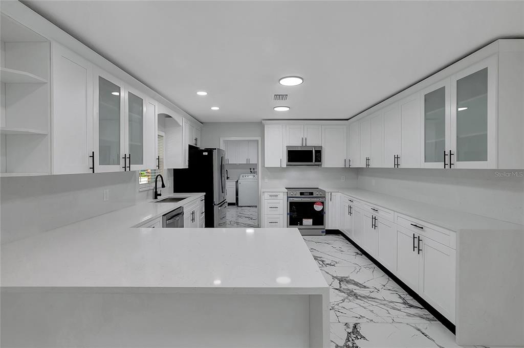 604 Druid Hills Road Temple Terrace, FL 33617 - Photo 17 of 59 a large white kitchen with stainless steel appliances refrigerator a sink and microwave