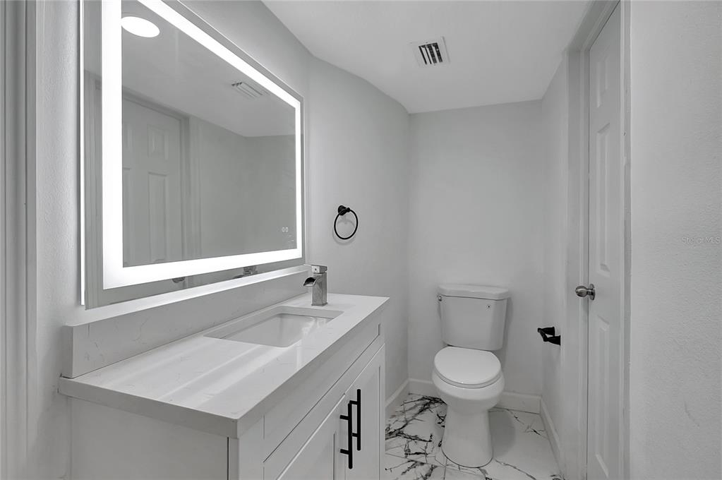 604 Druid Hills Road Temple Terrace, FL 33617 - Photo 26 of 59 a bathroom with a toilet a sink a mirror and a window