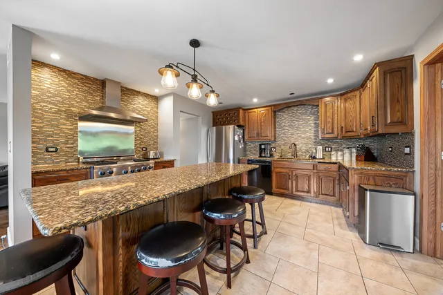 a kitchen with stainless steel appliances granite countertop table chairs sink and cabinets
