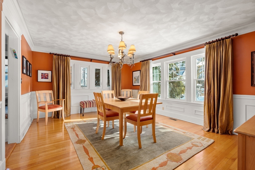 23 Newman Way, Unit 1 Arlington, MA 02476 - Photo 7 of 28 a dining room with wooden floor a chandelier a wooden table and chairs