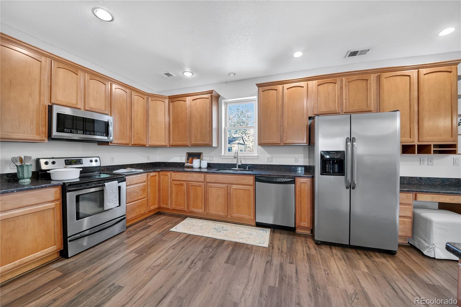 665 Kilmer Street Golden, CO 80401 - Photo 14 of 35 a kitchen with granite countertop wooden floors stainless steel appliances a sink and a window