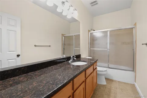 a bathroom with a granite countertop sink a toilet a mirror and shower