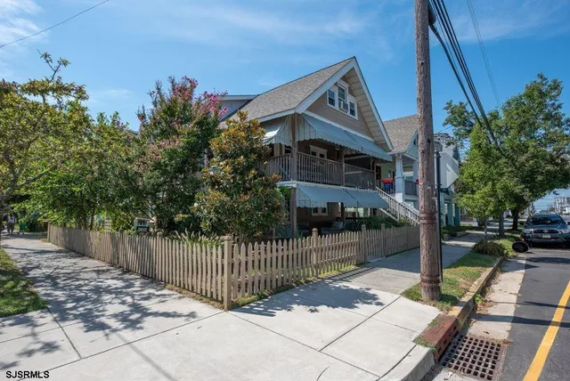 a view of a house with a small yard and wooden fence