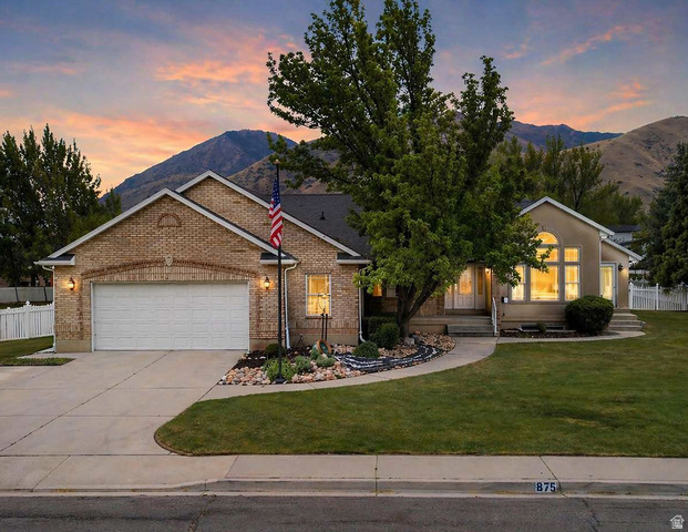 View of front of home with an attached garage, a mountain view, driveway, and brick siding