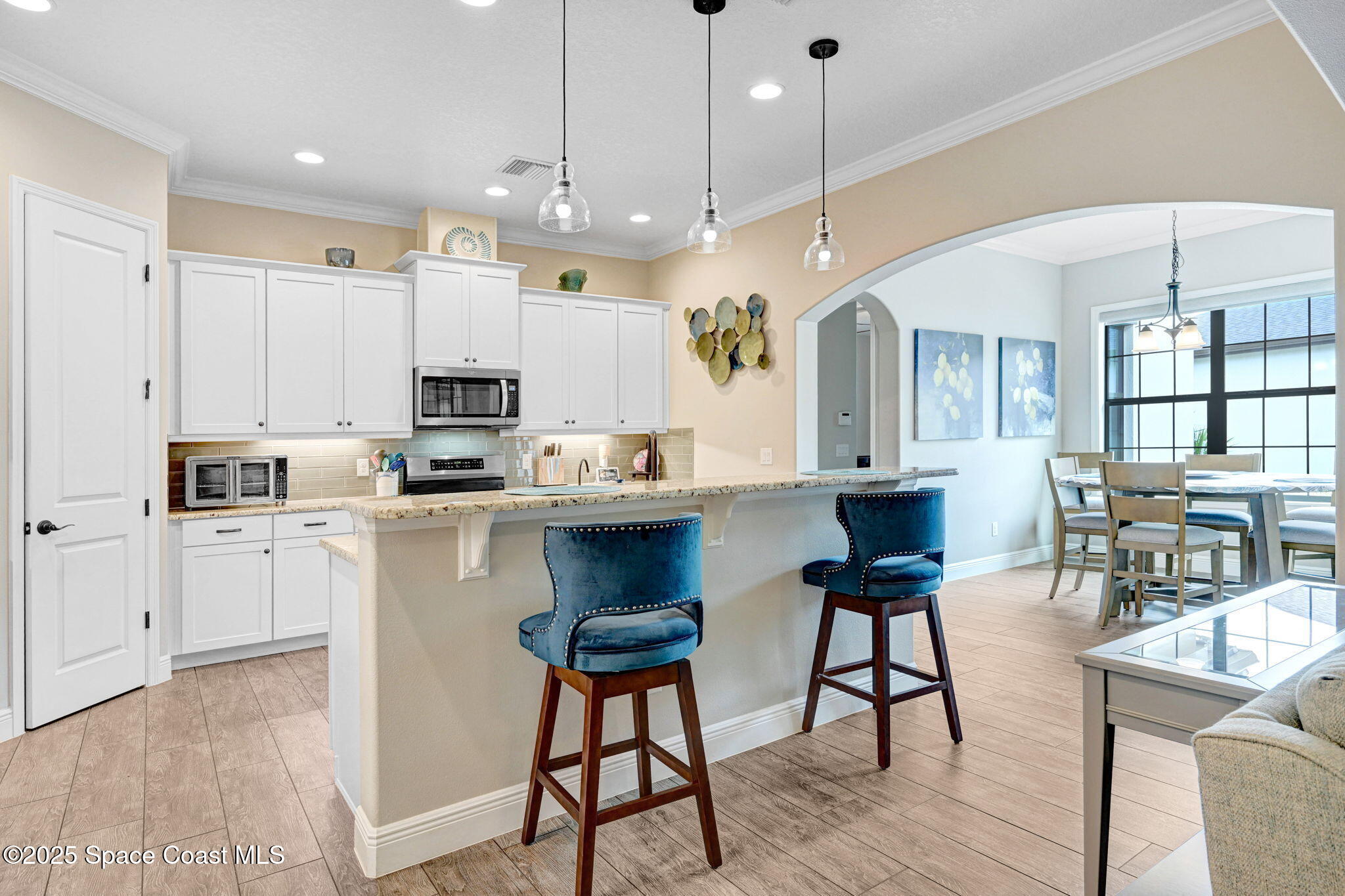 7072 Mercado Lane Melbourne, FL 32940 - Photo 6 of 32 a kitchen with kitchen island a dining table chairs and white cabinets