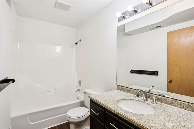 a bathroom with a granite countertop sink toilet a large mirror a shower and a bathtub