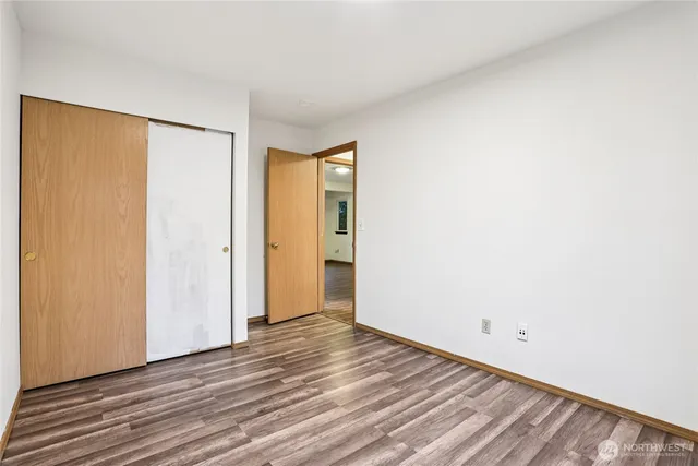 a view of an empty room with wooden floor and closet